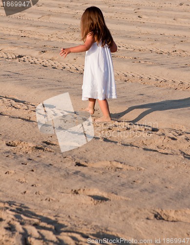 Image of little cute girl smiling playing on beach in summer