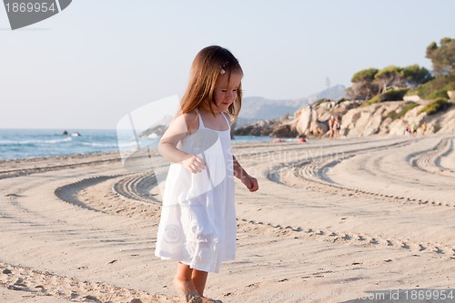 Image of little cute girl smiling playing on beach in summer