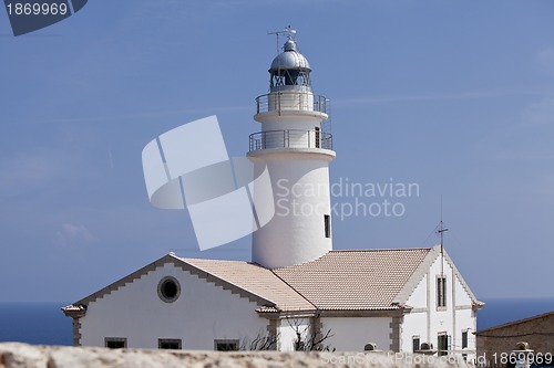 Image of white lighthouse on rocks in the sea ocean water sky blue