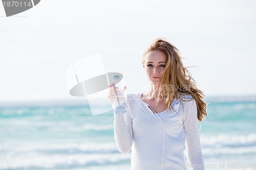 Image of beautiful young woman drinking water in summer 