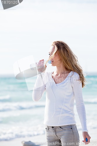 Image of beautiful young woman drinking water in summer 