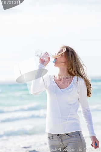 Image of beautiful young woman drinking water in summer 