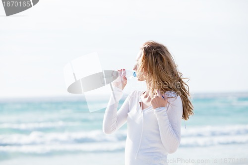 Image of beautiful young woman drinking water in summer 