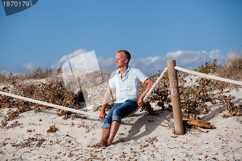 Image of young man is relaxing outdoor in dune in summer