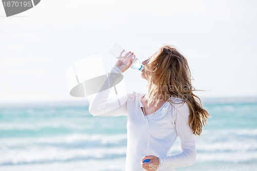 Image of beautiful young woman drinking water in summer 