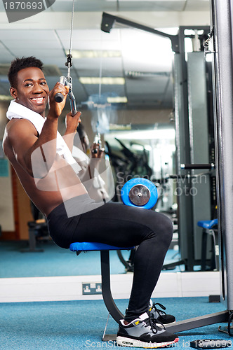 Image of Fit african trainer working out in multi gym