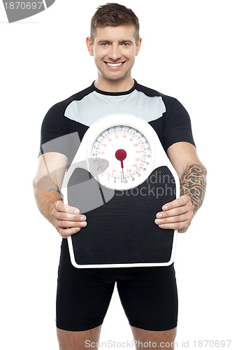Image of Smart young fit male showing weighing machine