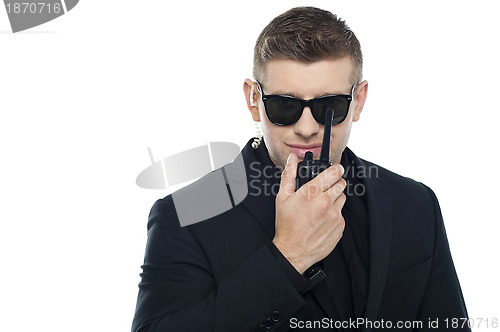 Image of Smart young security personnel communicating over the walkie-talkie