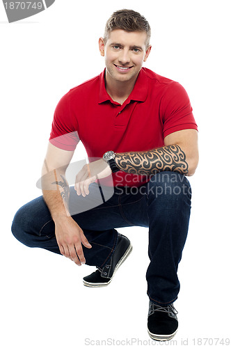 Image of Young man sitting in squatting position