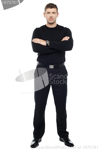 Image of Young smart bouncer posing with his arms crossed .