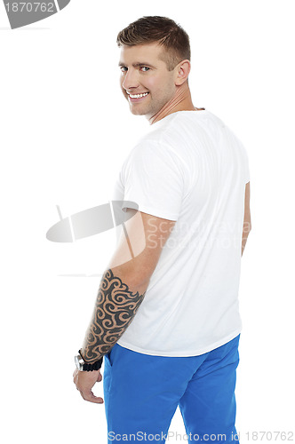 Image of Young smiling man with tattoo on hand turning back