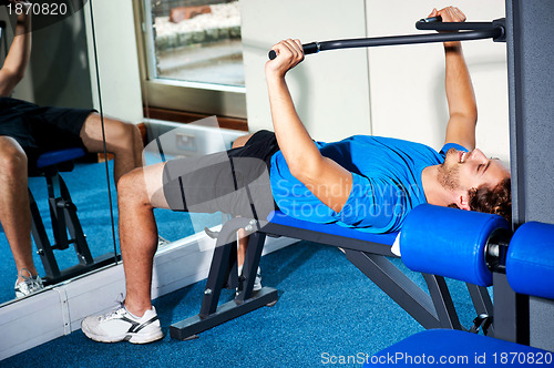 Image of Fitness guy lying on bench and exercising