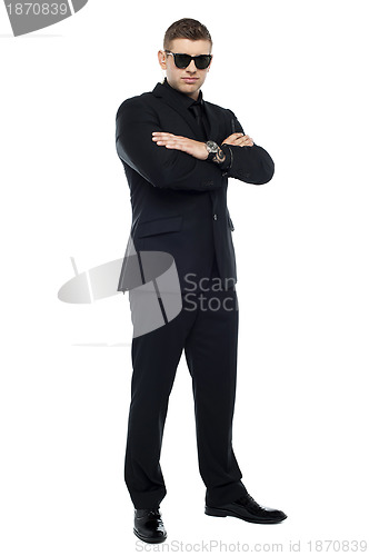 Image of Young stylish bouncer in a black suit, arms folded