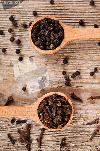 Image of black pepper and cloves in wooden spoons