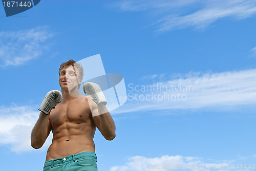 Image of Young guy in boxing gloves training outdoors