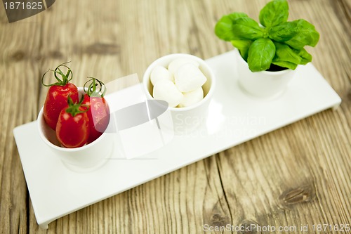 Image of tasty tomatoes mazarella and basil on plate on table