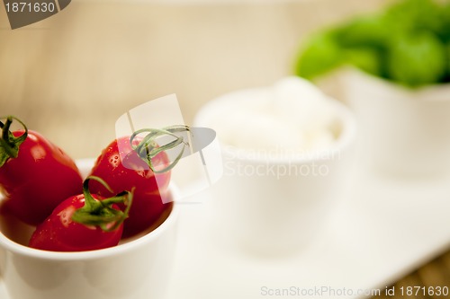 Image of tasty tomatoes mazarella and basil on plate on table