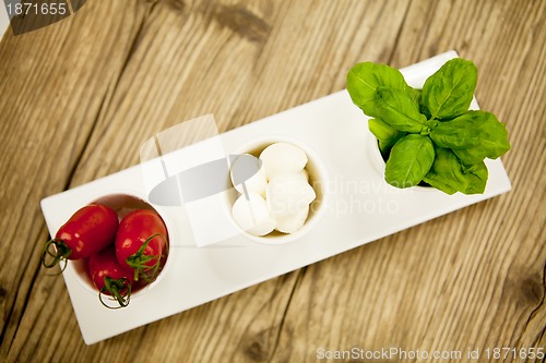 Image of tasty tomatoes mazarella and basil on plate on table