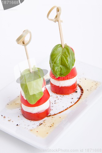 Image of tasty tomatoe mozzarella salad with basil on white 