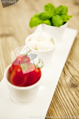 Image of tasty tomatoes mazarella and basil on plate on table