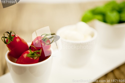 Image of tasty tomatoes mazarella and basil on plate on table