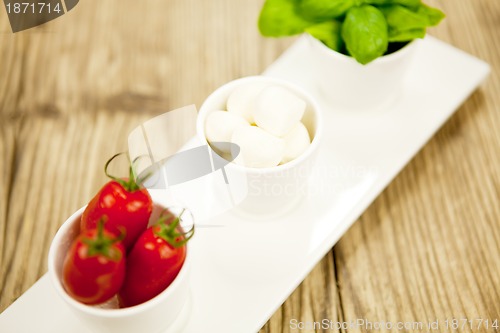 Image of tasty tomatoes mazarella and basil on plate on table