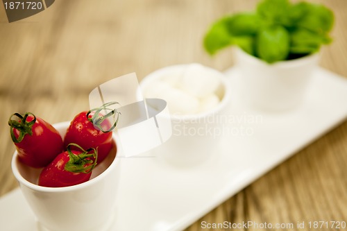 Image of tasty tomatoes mazarella and basil on plate on table