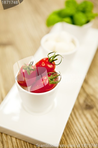 Image of tasty tomatoes mazarella and basil on plate on table