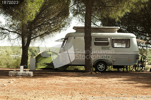 Image of Small white caravan through the trees