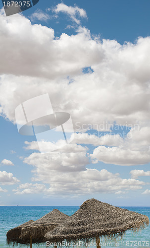 Image of Large blue sky with clouds.Straw umbrellas