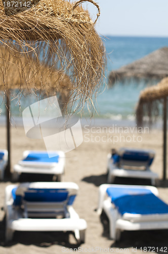 Image of Straw beach umbrellas and sunbeds