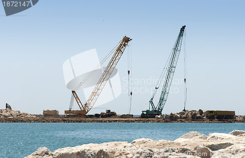 Image of Building a dike. Cranes and excavator put stones