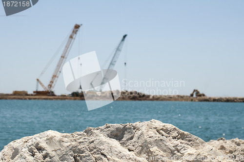 Image of Building a dike. Cranes and excavator put stones