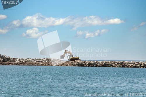 Image of Building a dike. Excavator put stones