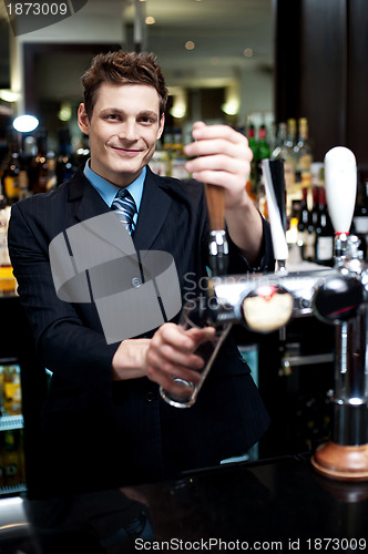 Image of Handsome mixologist putting ice into tall glass