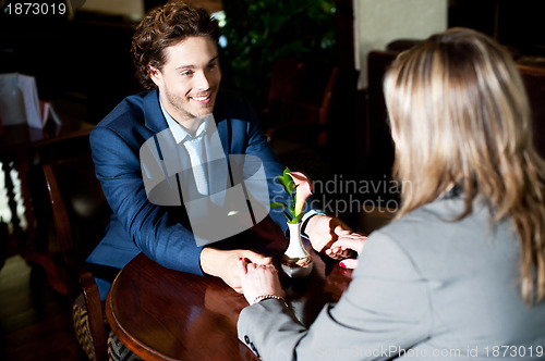 Image of Romantic couple sitting across the table and holding hands