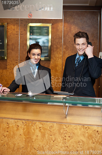 Image of Male and female at hotel reception busy working