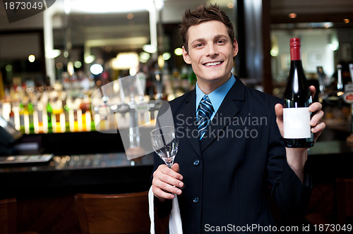 Image of Cheerful executive posing with a bottle of wine