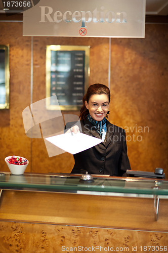 Image of Female receptionist handing over check-out papers