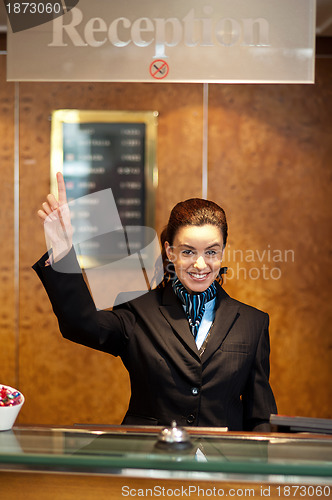 Image of Beautiful female receptionist indicating upwards