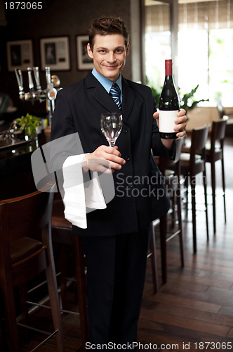 Image of Man posing with a bottle of wine in restaurant