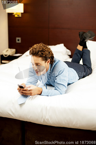 Image of Man reading messages on his phone after long work day