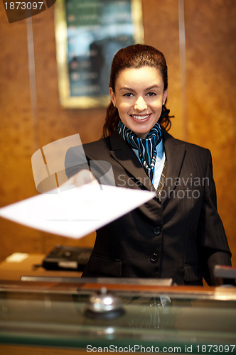 Image of Cheerful female receptionist offering check-in papers