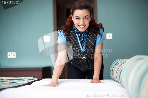 Image of Smiling female executive giving final touches to master bedroom