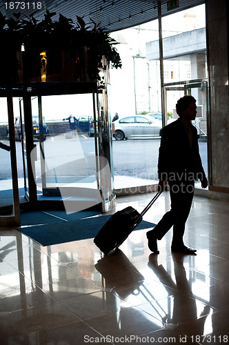 Image of Man entering hotel lobby with his luggage