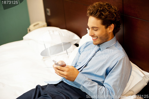 Image of Cool guy reading funny message on his cellphone