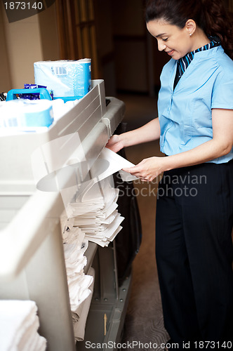 Image of Back-office female employee folding sheets