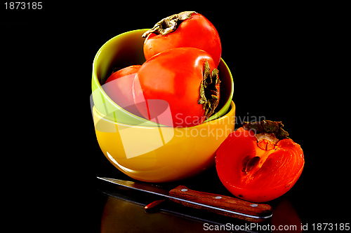 Image of Juicy persimmon in a bowl and knife.