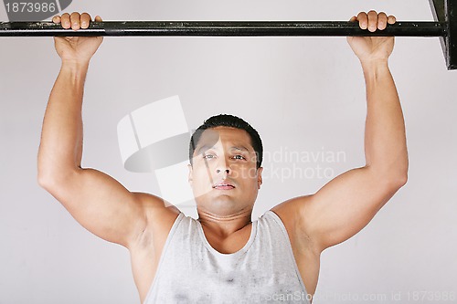 Image of Athlete pull oneself up on gym background 