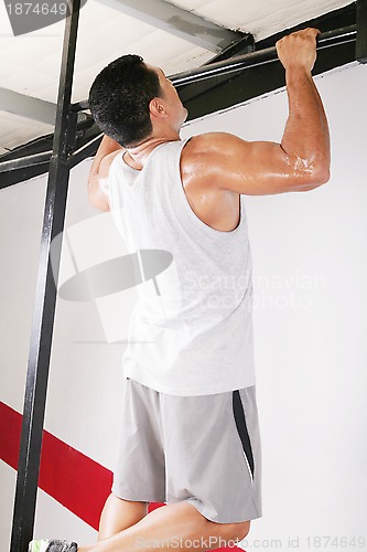 Image of strong man performing pull ups in a bar 